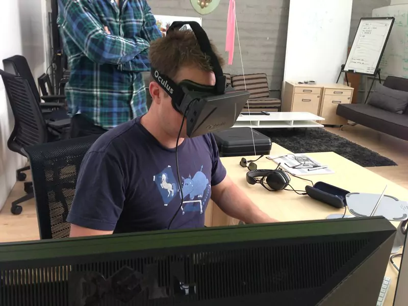 Man using VR Headset while sitting on computer desk